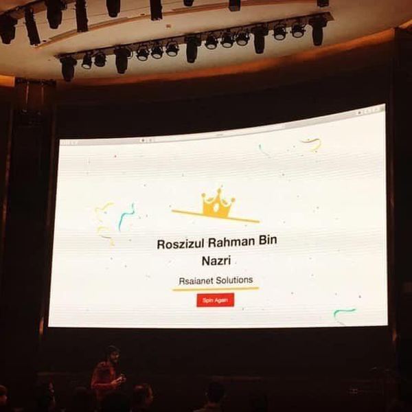 Large screen at the MikroTik User Meeting Malaysia 2019 displaying a prize draw result for RSAIANet Solutions